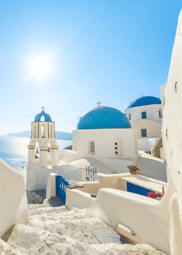 White buildings with blue domes under bright sky