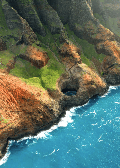 Aerial view of colorful coastal cliffs and ocean.