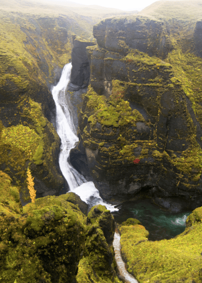 Waterfall cascading through moss-covered rocky cliffs.