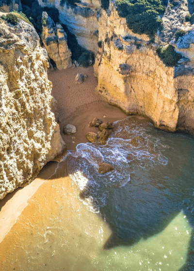 Aerial view of a sandy beach and rocky cliffs.
