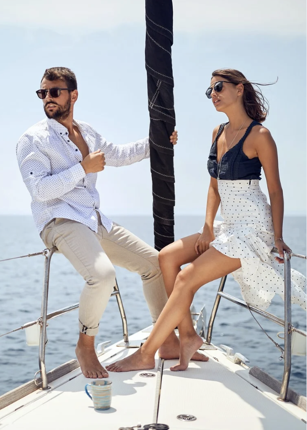 Couple relaxing on a sailboat in sunshine.