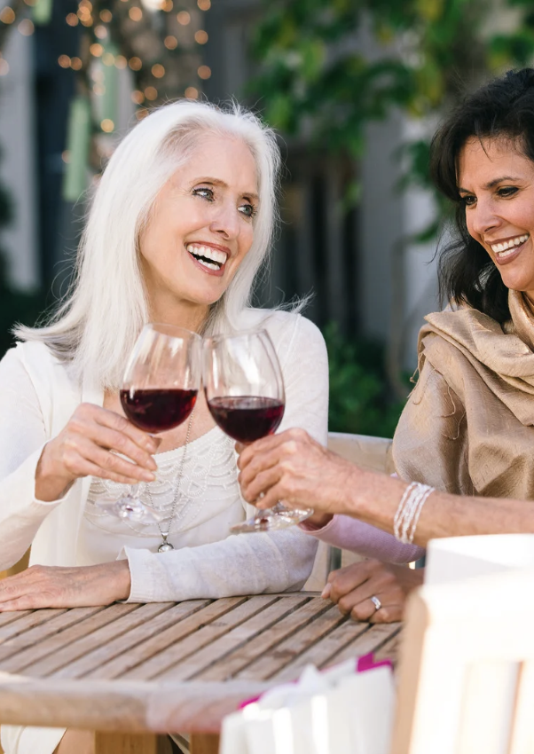 Two women toasting with glasses of red wine.