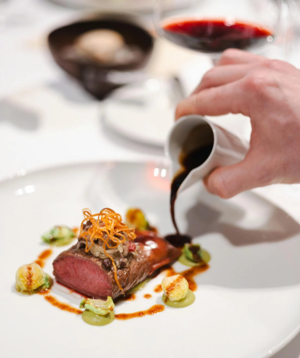 Gourmet dish with meat and sauce being poured