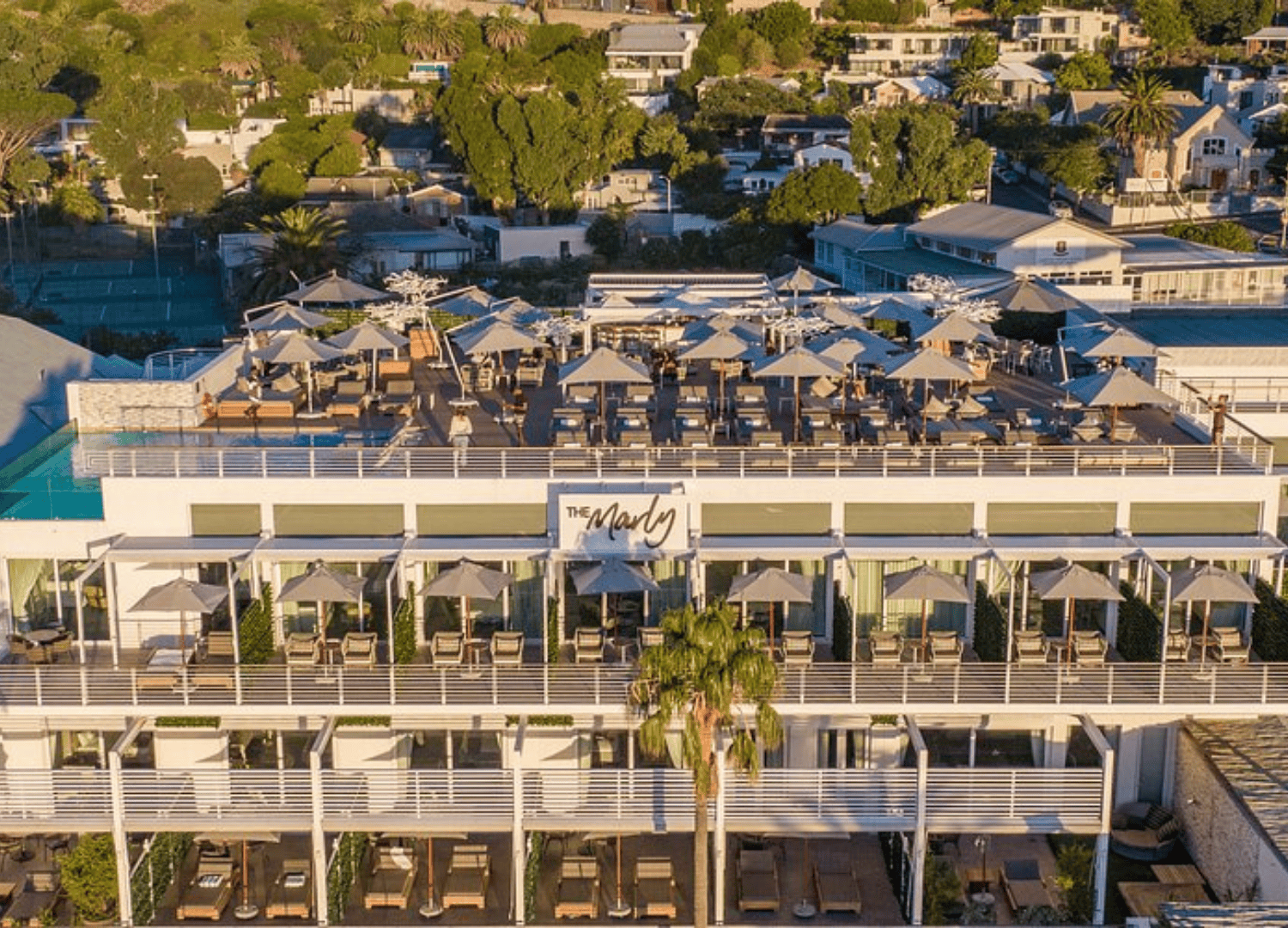 Rooftop restaurant with umbrellas overlooking residential area.