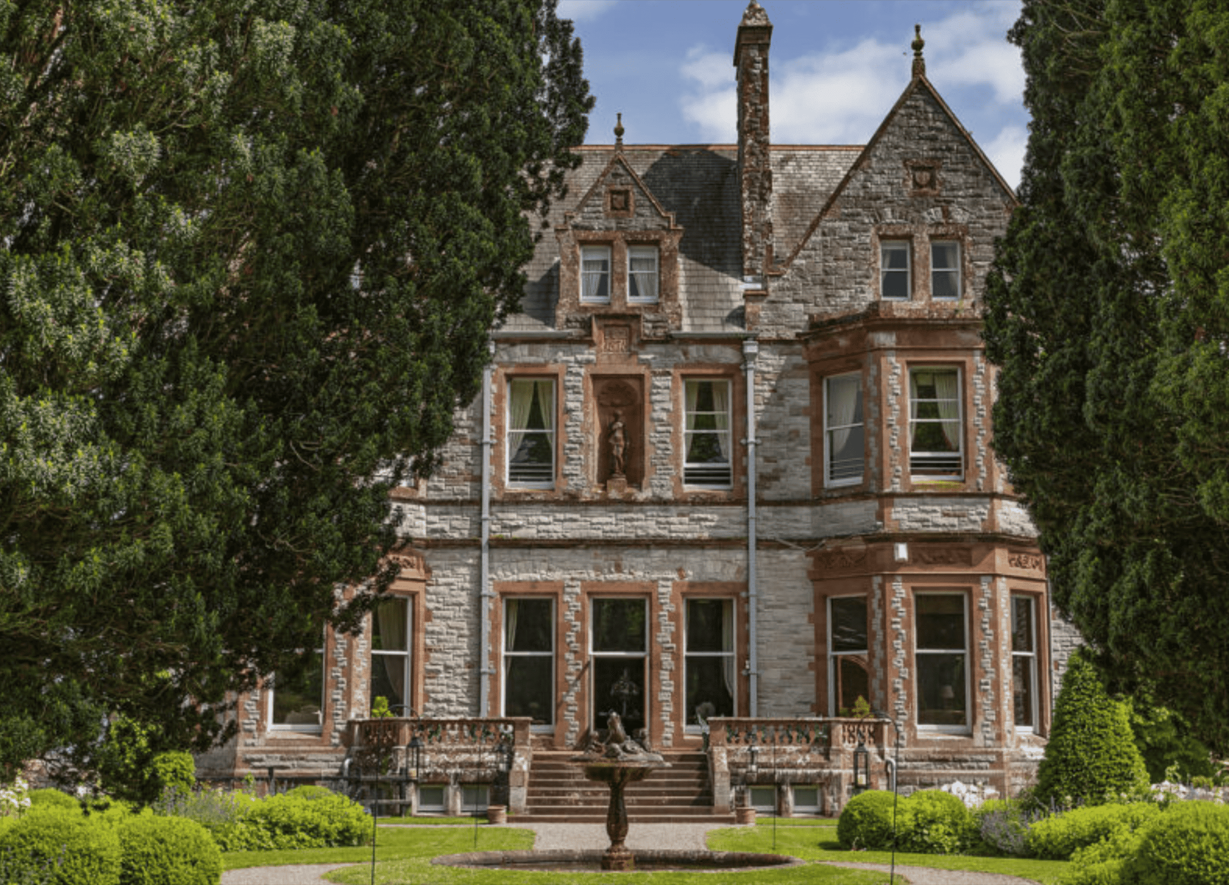 Historic stone mansion surrounded by lush gardens
