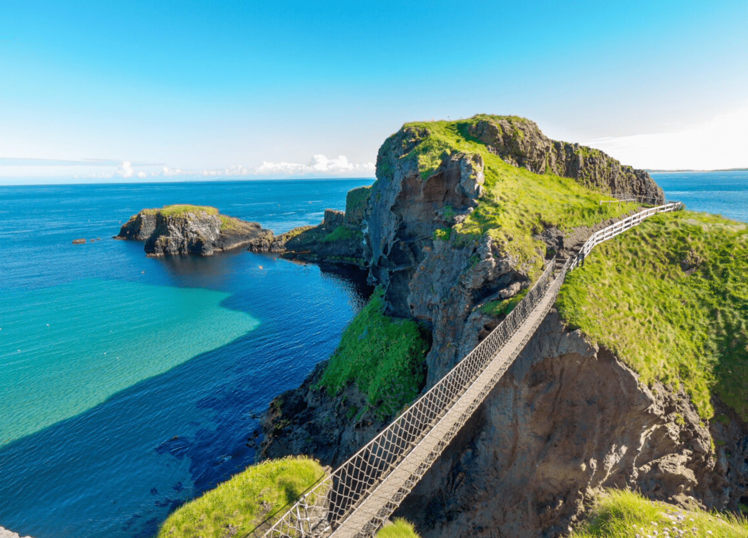 Scenic coastal cliff with rope bridge and ocean view.