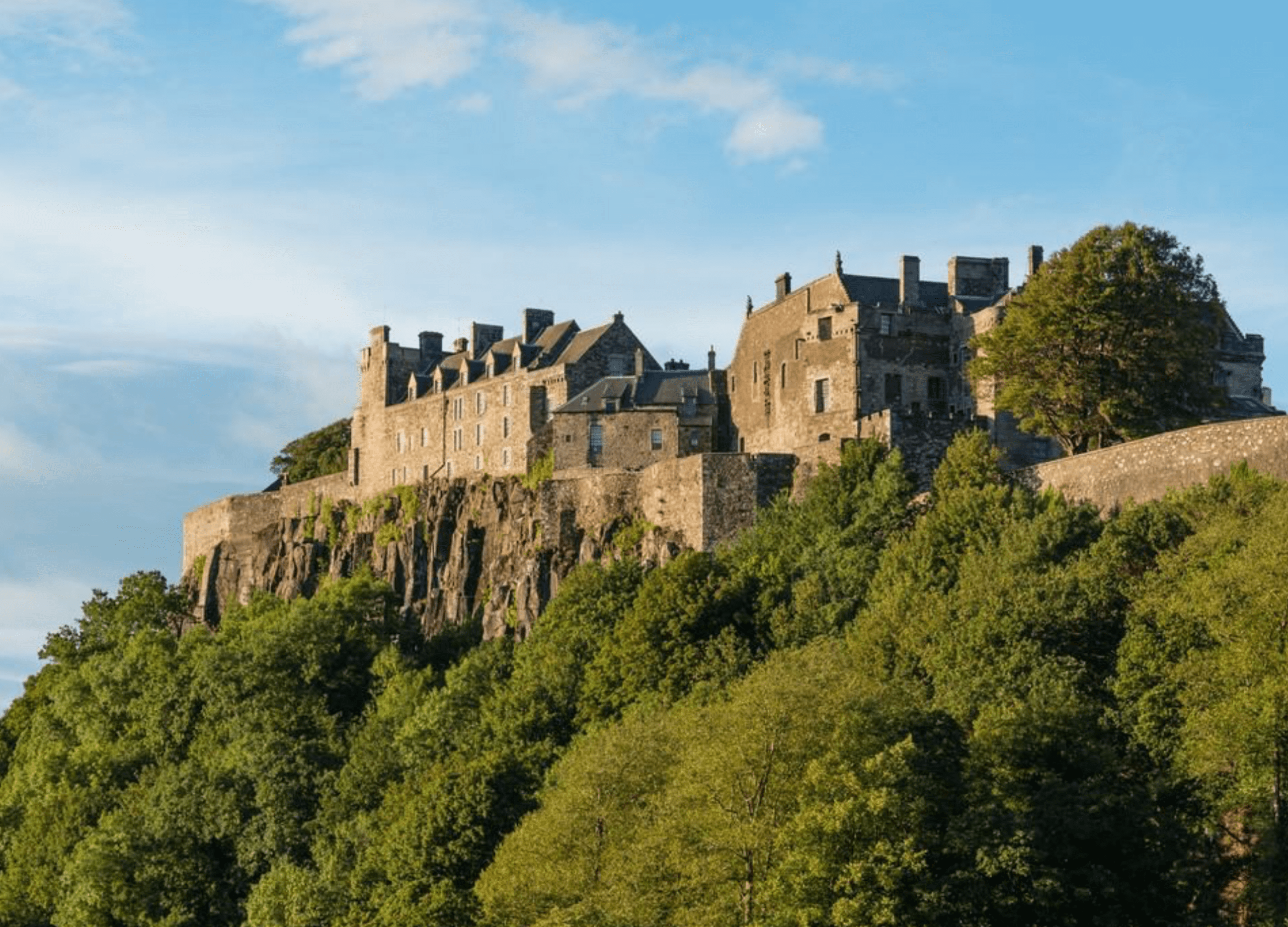 Historic castle on a hilltop under blue sky.