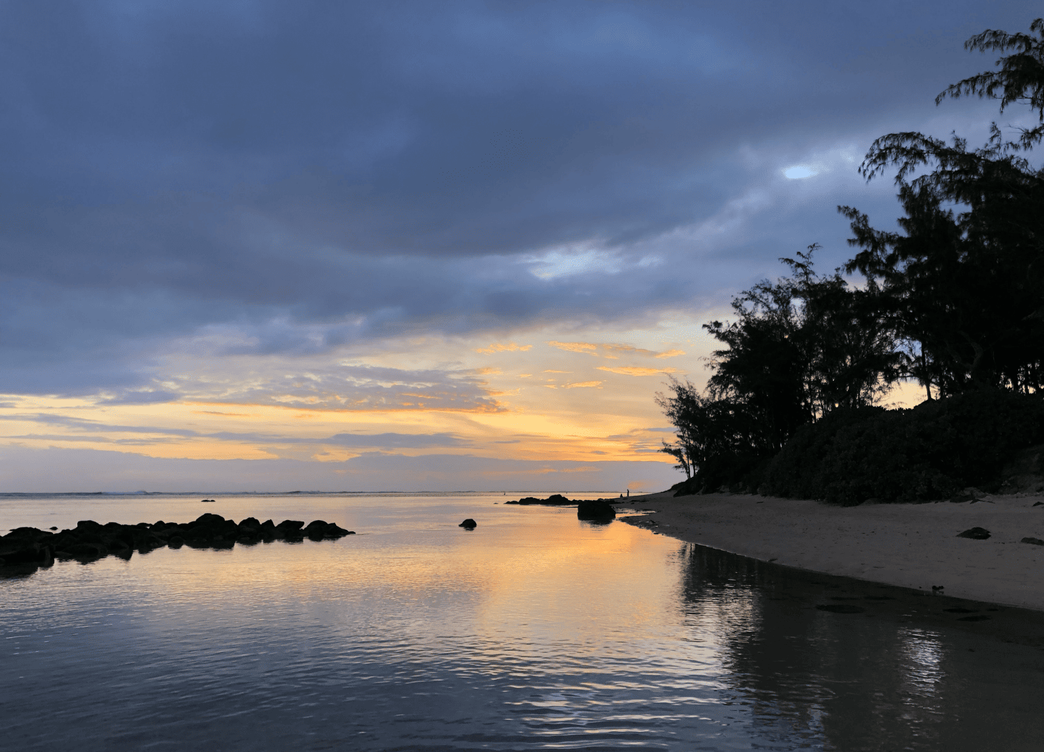 Tranquil beach sunset with cloudy sky.