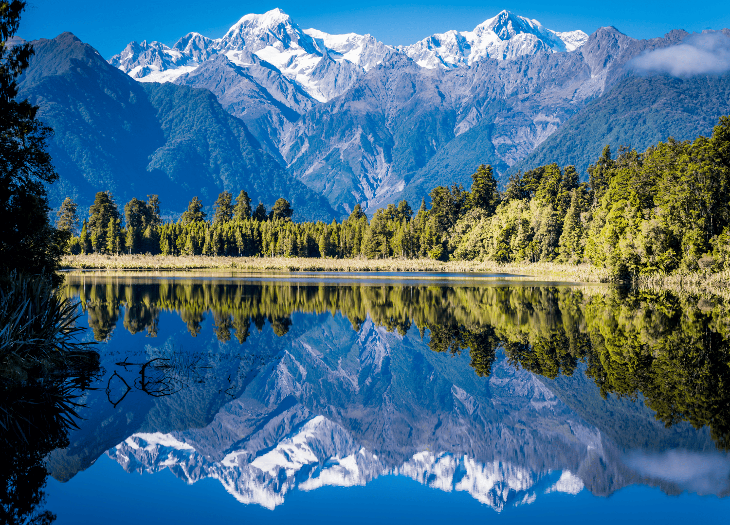 Snowy mountains reflected in calm lake water
