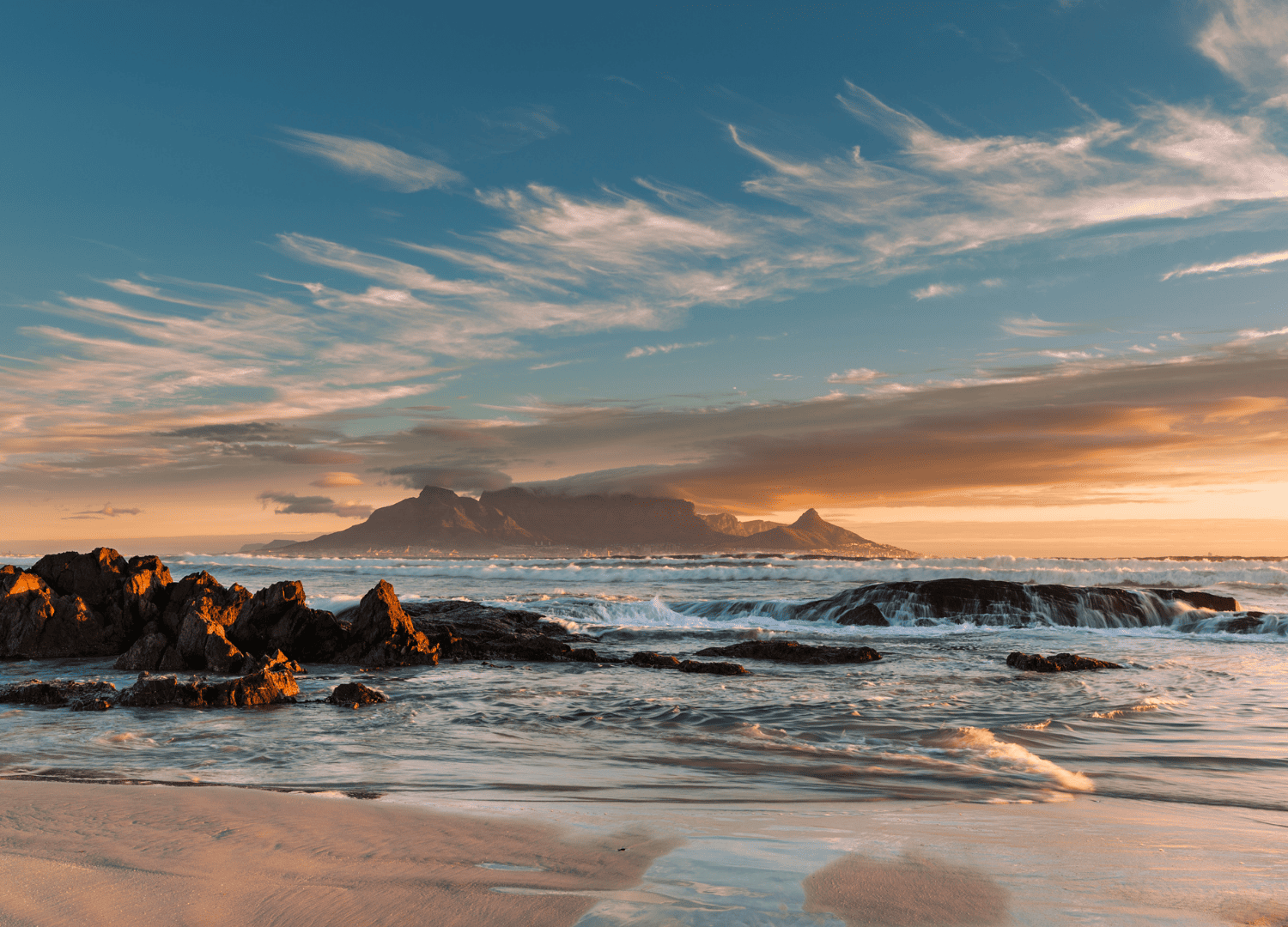 Sunset over rocky beach and distant mountains