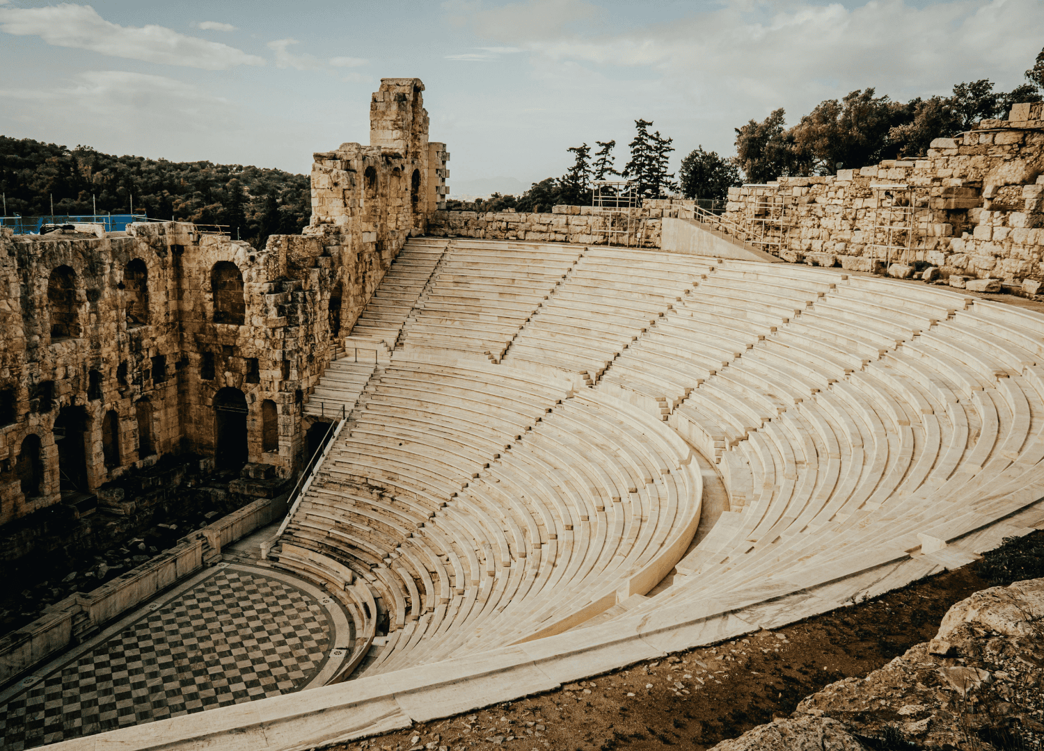 Ancient Greek amphitheater with stone steps and arches.