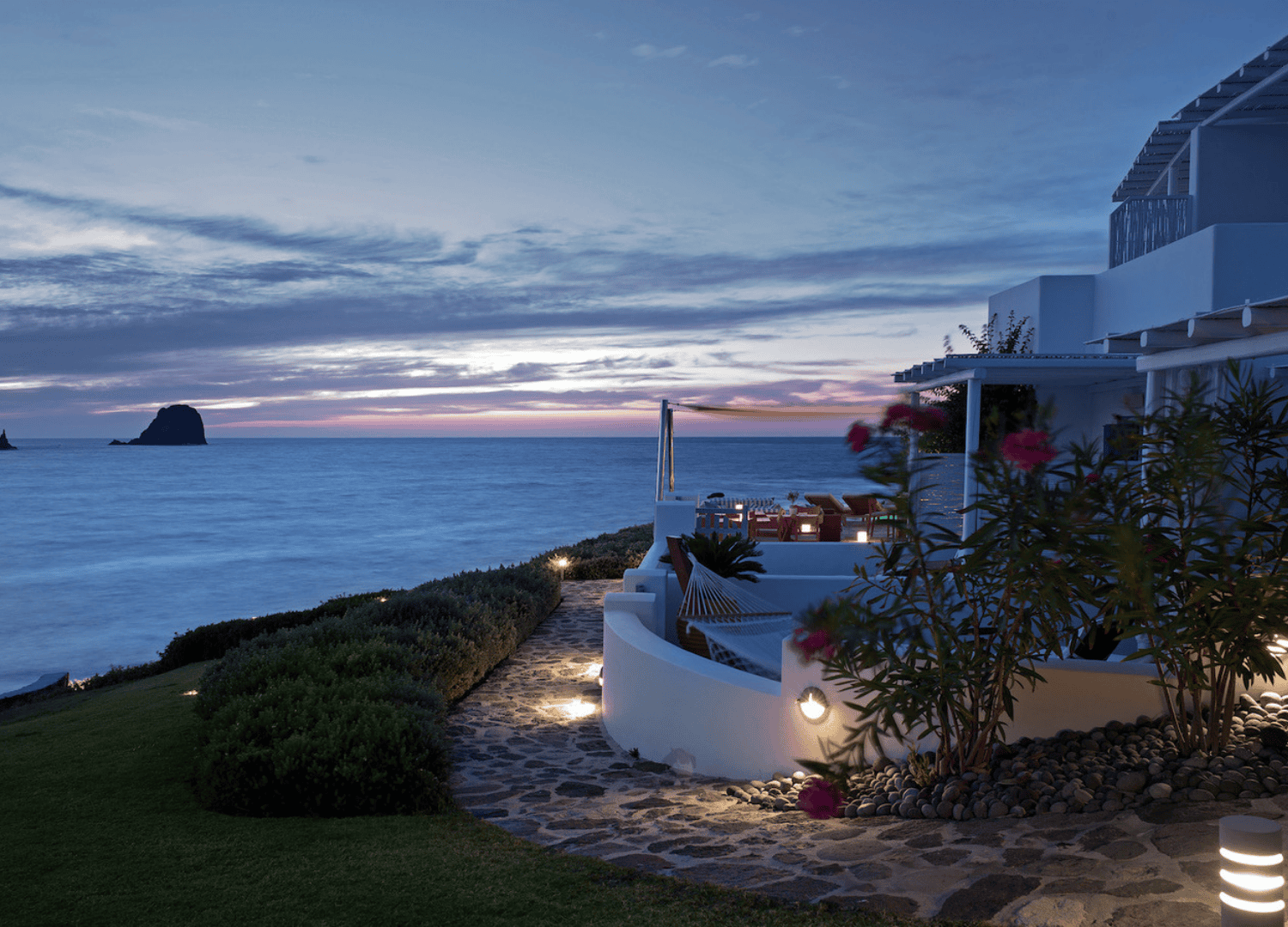Oceanfront house at sunset with garden path view.