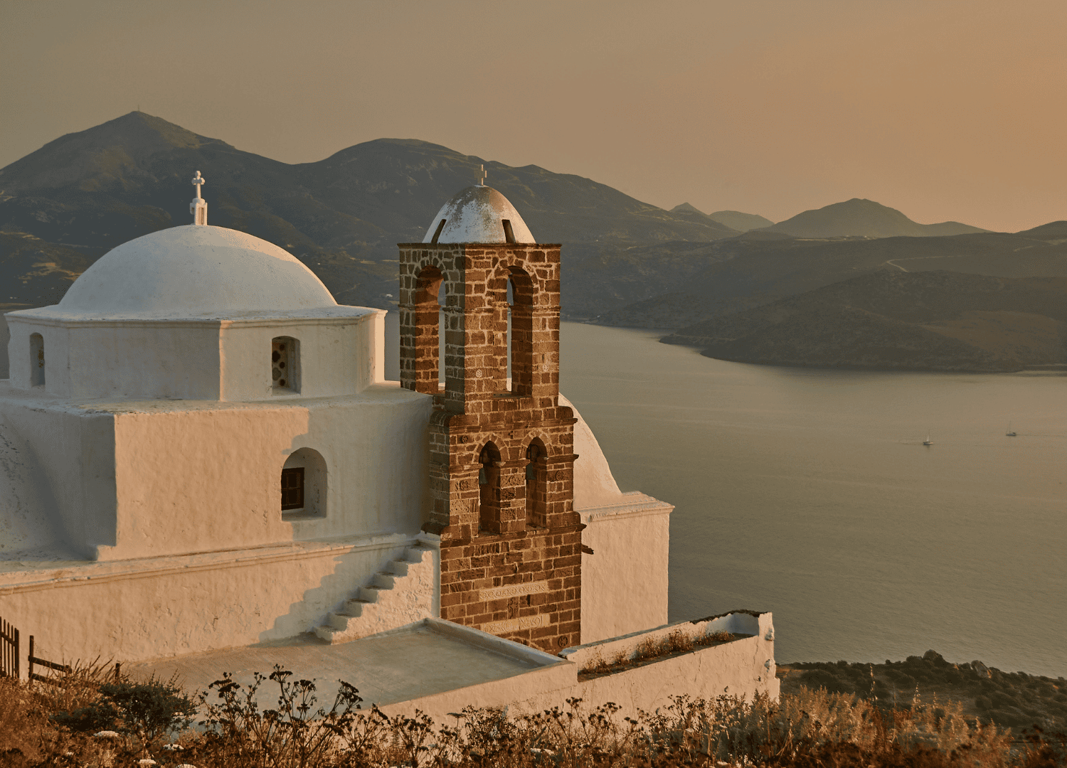 Sunset view of church in Greek island landscape.