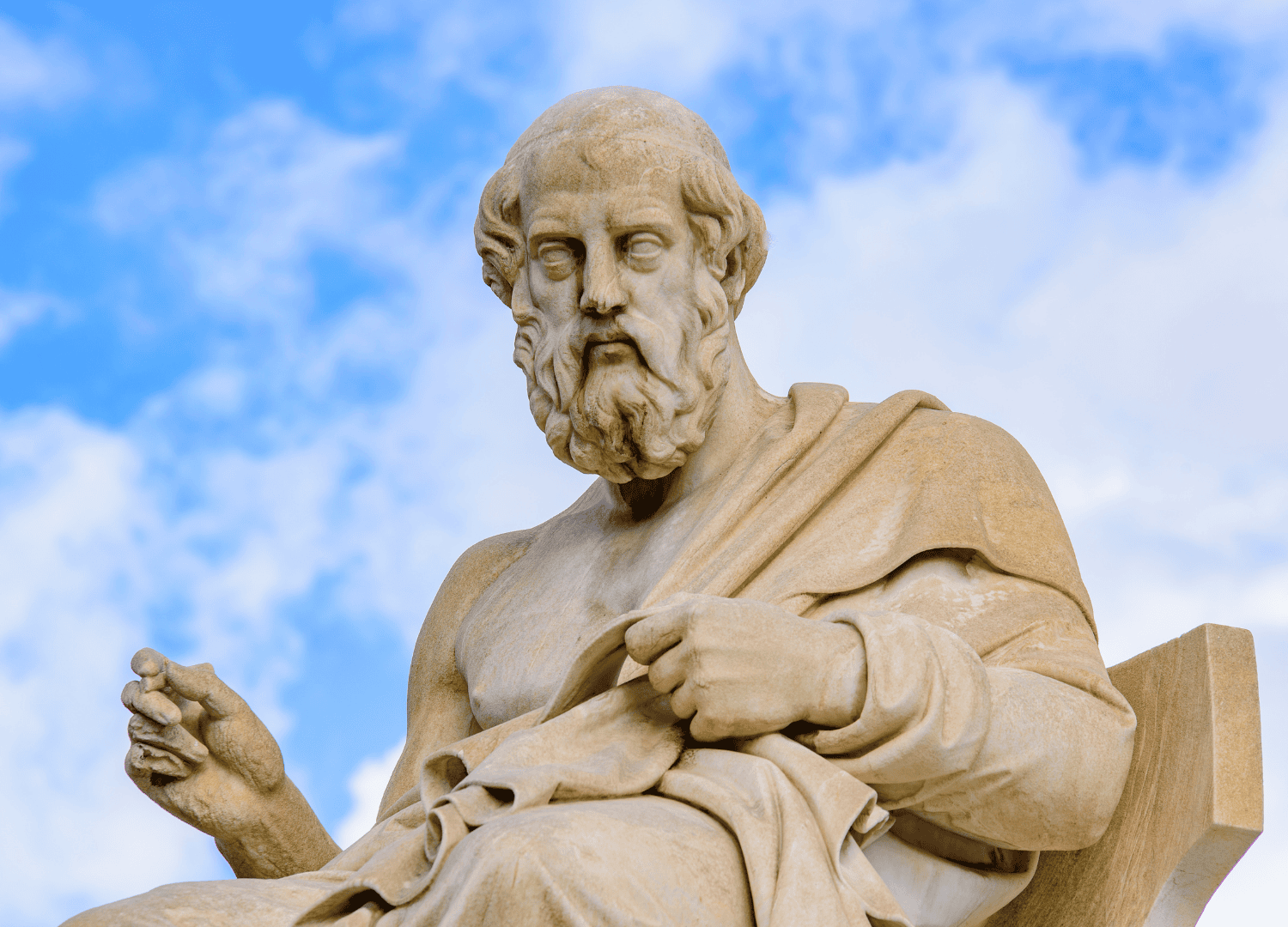 Ancient philosopher statue against blue sky.