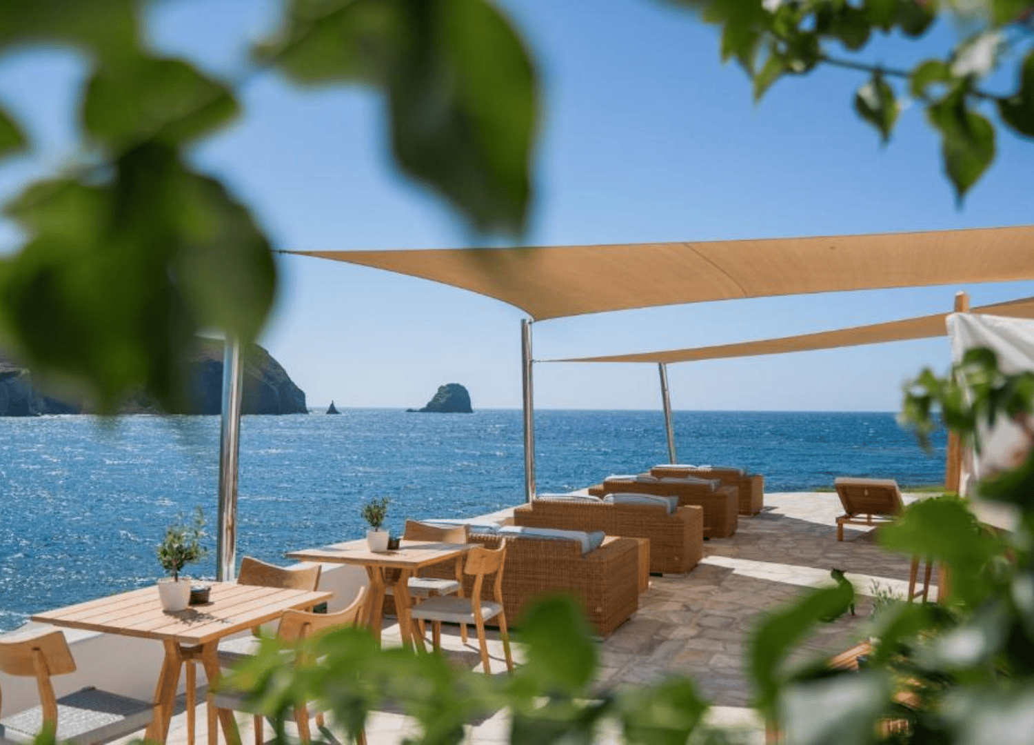 Seaside patio with ocean view and tables.