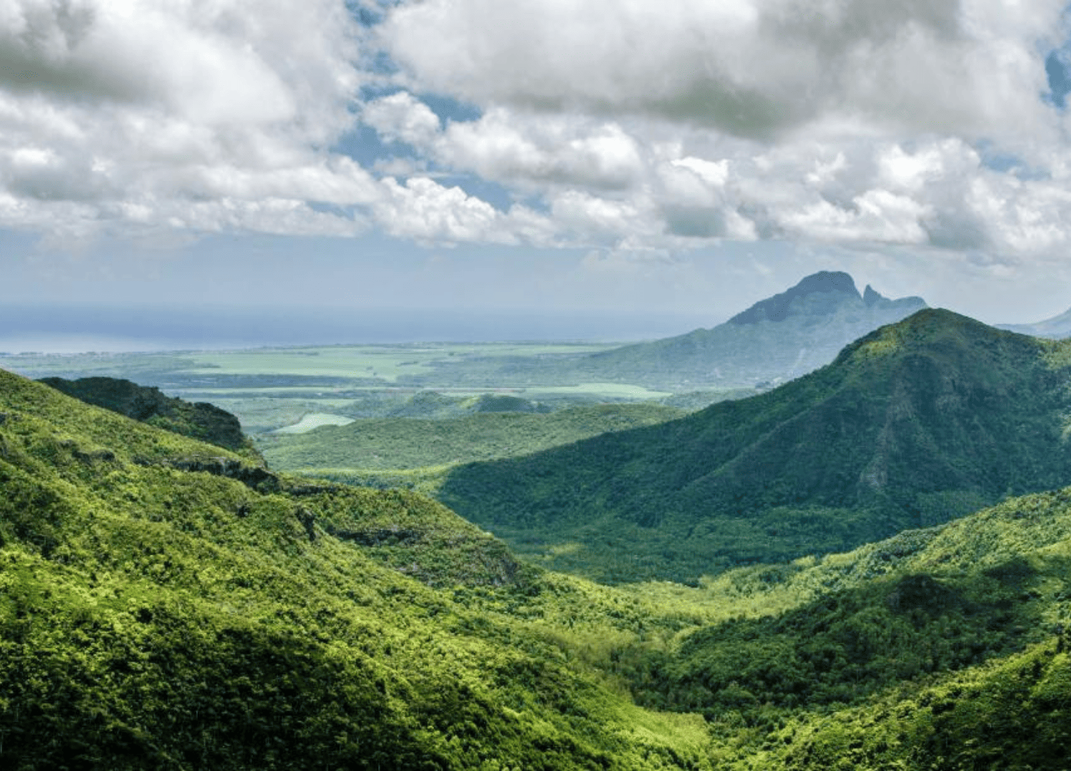 Green mountains under cloudy sky scenic view.