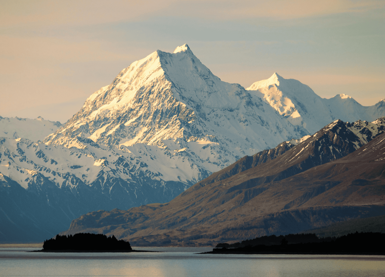 Snowy mountain peak under clear sky at sunset.