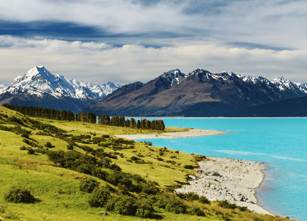 Snowy mountains and lake under cloudy sky.