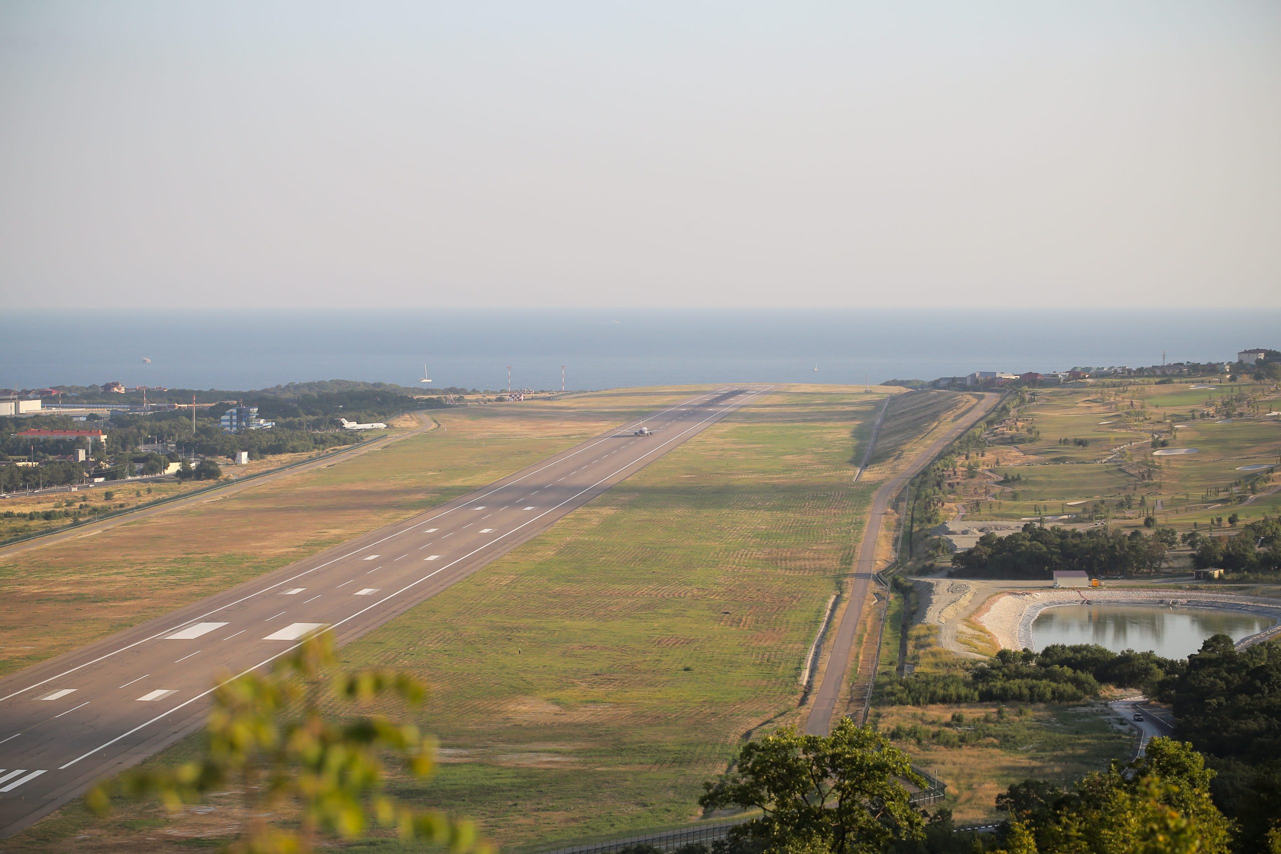 Runway near ocean, trees, and landscape.